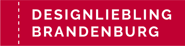 Logo Designliebling Brandenburg. Weiße Schrift auf rotem Untergrund, links vom Schriftzug eine senkrechte gestrichelte Linie