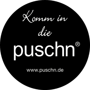 Logo von Puschs. Weiße Schrift im schwarzen Kreis: "Komm in die puschen. www.puschn.de"